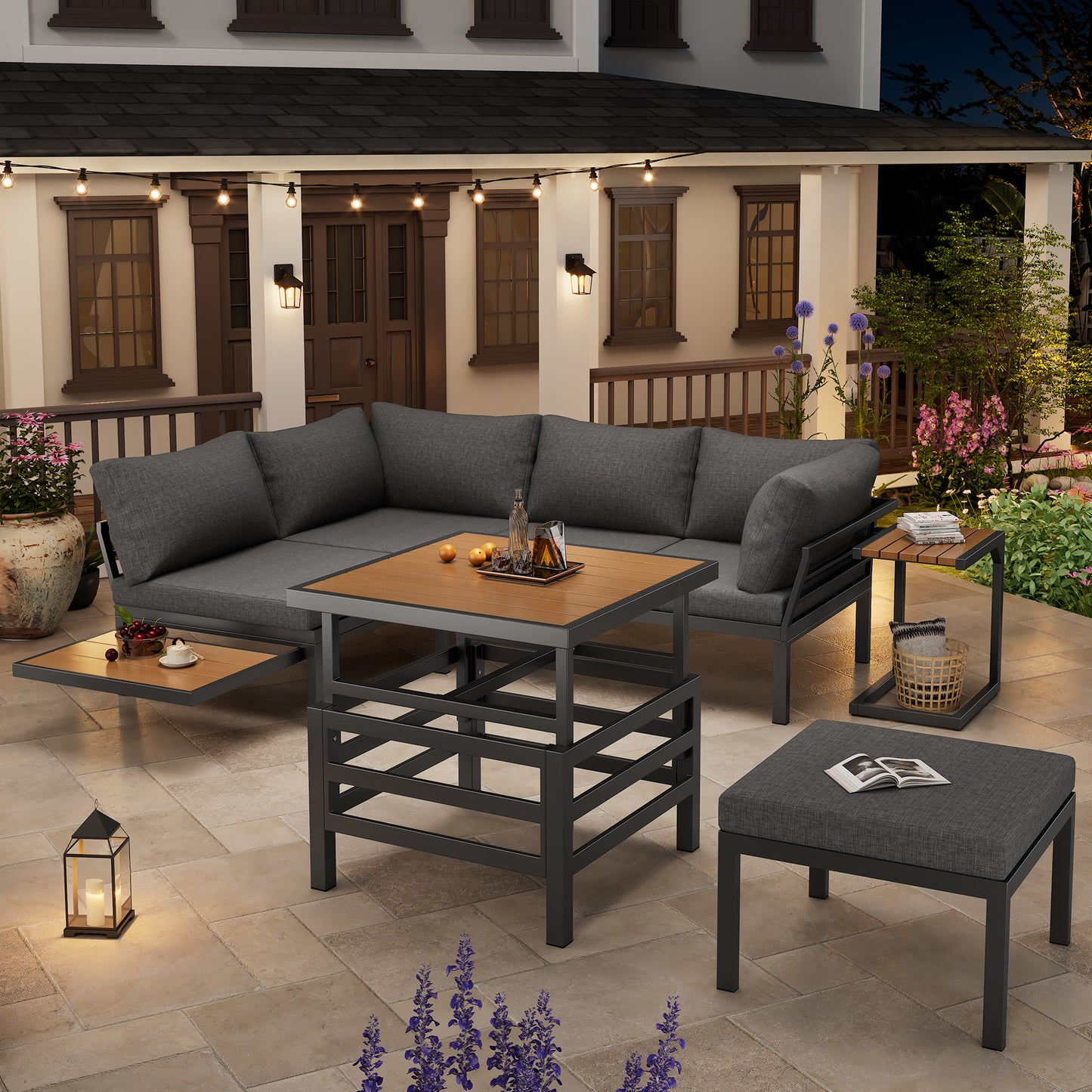Outdoor patio set with gray sectional sofa, coffee table, and ottoman on a stone patio.